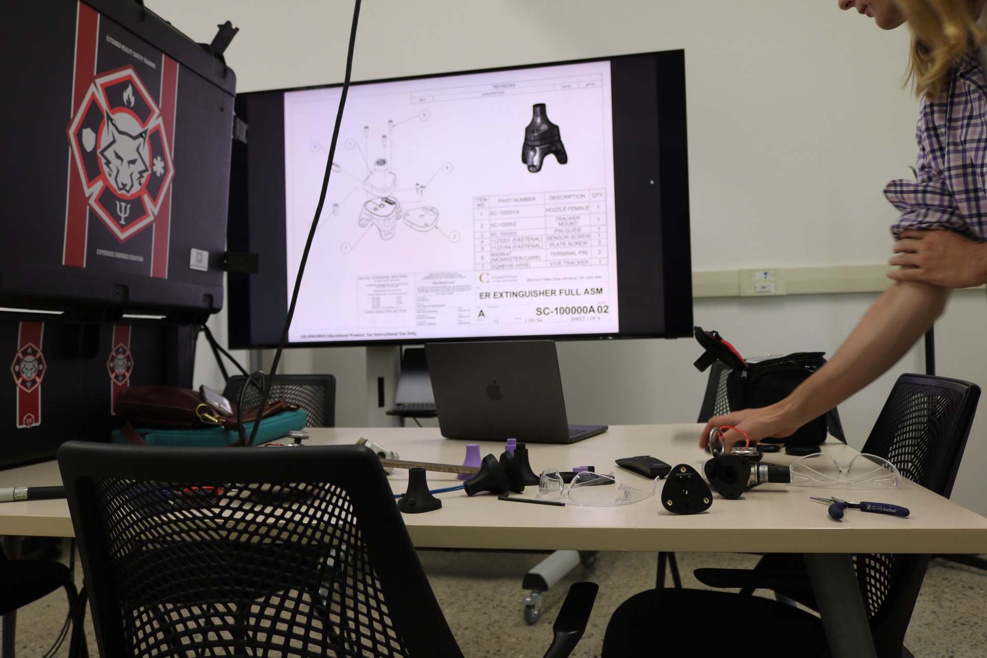 A monitor showing the full XR extinguisher CAD assembly drawing next to the Catapult Tactical XR hardware case