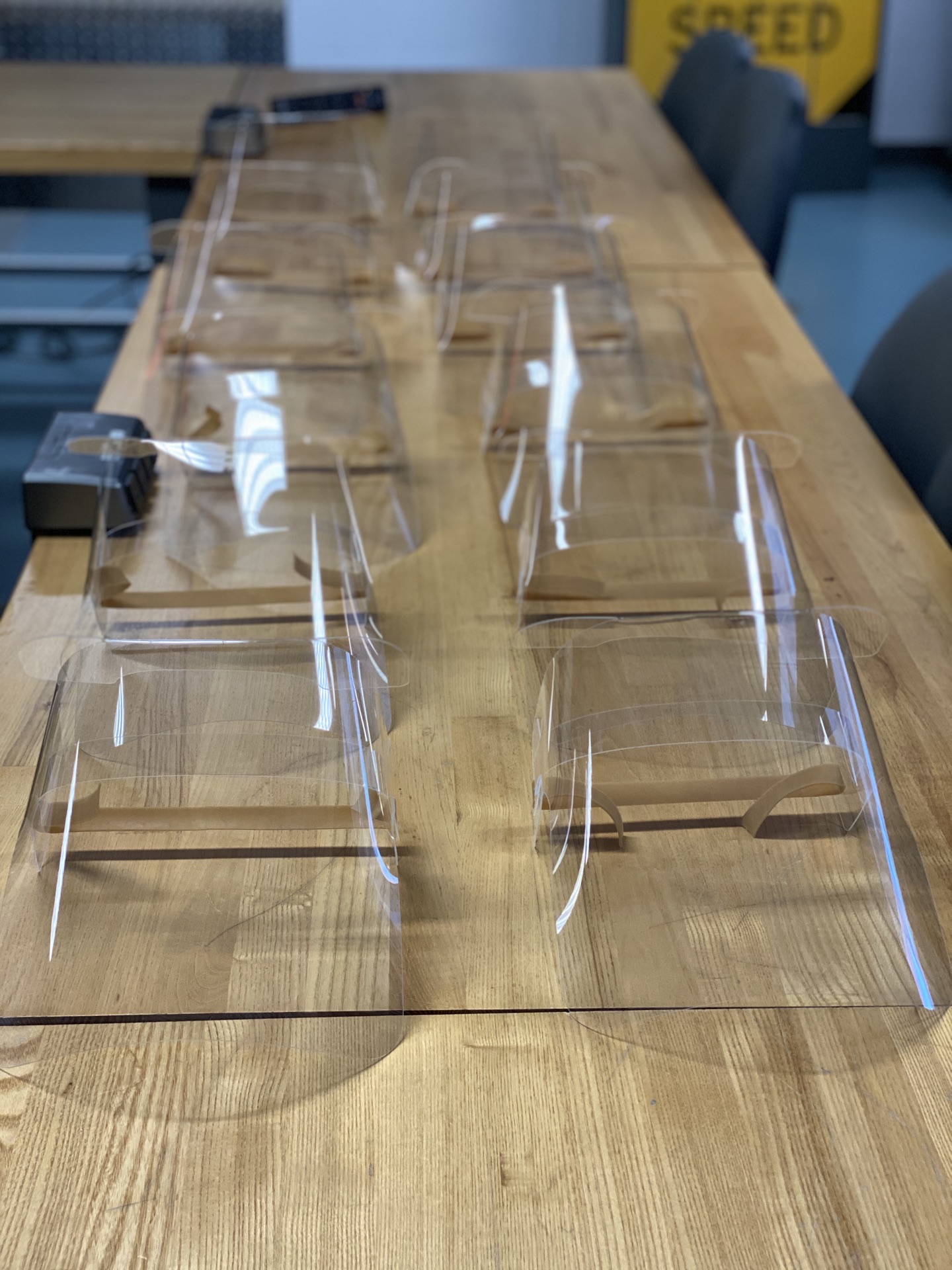 Rows of assembled foldable PETG face shields on the workbench